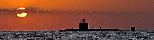 A submarine returns to surface as the sun is setting.