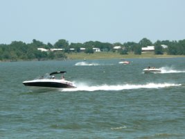 Speed boats racing across the lake on a sunny day.