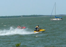 Two jet skies cross as they travel about the lake.