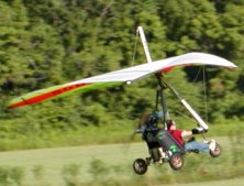A powered hang-glider arrives.